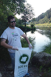 Michael holding a SOLVE Oregon cleanup bag standing in front of the Tyee section of the Umpqua river.